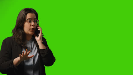 Frustrated-Young-Businesswoman-Wearing-Glasses-Talking-On-Mobile-Phone-Against-Green-Screen-Studio-Background-1